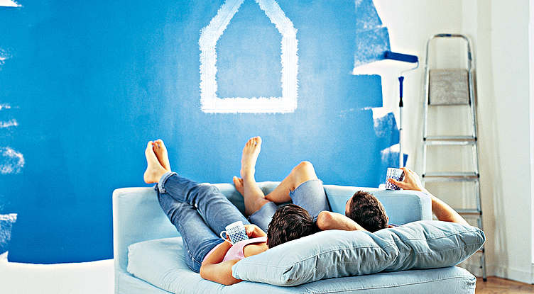 Immobilienfinanzierung - Paar schaut vom Sofa auf gestrichene Wand